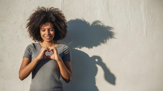 Foto mujer haciendo sombra de corazón en la pared día mundial de la salud mental esperanza y amor