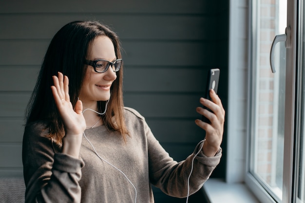 Mujer haciendo videollamadas con smartphone en casa