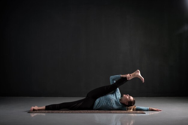 Mujer haciendo yoga asana Anantasana o Levantamiento de pierna reclinable lateral