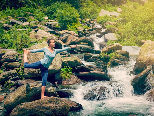 Foto mujer haciendo yoga asana natarajasana al aire libre en la cascada