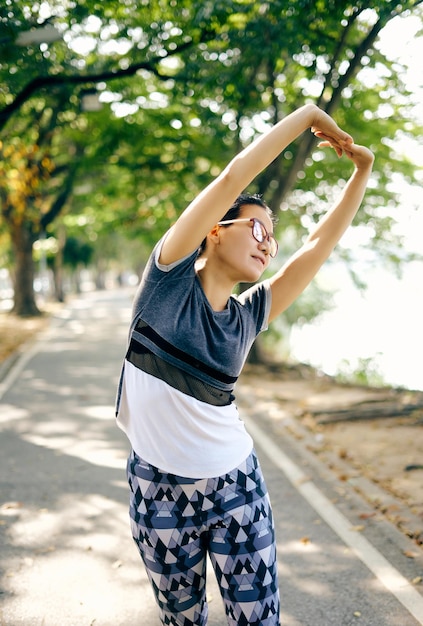 Mujer haciendo yoga en la carretera contra los árboles