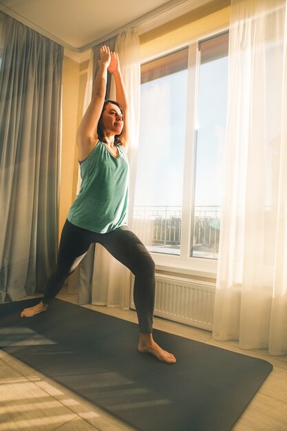 Mujer haciendo yoga en casa cerca del espacio de copia de ventana