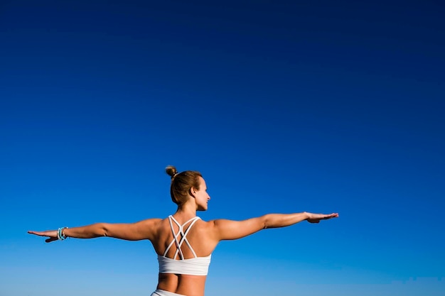 mujer haciendo yoga en un cielo azul en el fondo