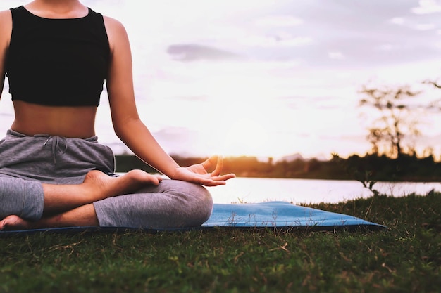 Mujer haciendo yoga junto al lago por la noche