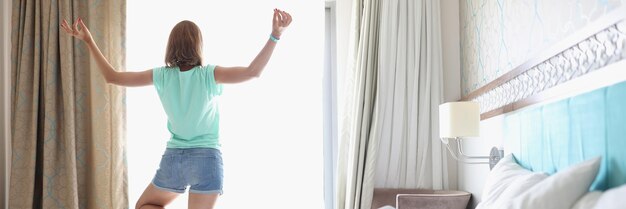 Mujer haciendo yoga junto a la ventana de luz en el dormitorio con un interior elegante