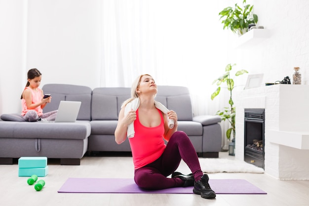 Foto la mujer está haciendo yoga en línea con una computadora portátil durante el autoaislamiento en su sala de estar, sin equipo de entrenamiento, consejos de meditación para principiantes. tiempo en familia con los niños, quédate en casa.