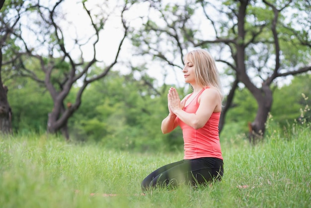 mujer haciendo yoga en el parque en verano