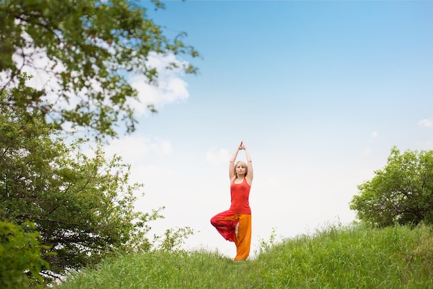 mujer haciendo yoga en el parque en verano