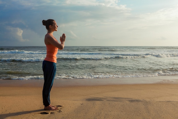 Mujer haciendo yoga en la playa