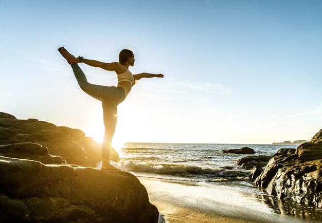 Mujer haciendo yoga en la playa
