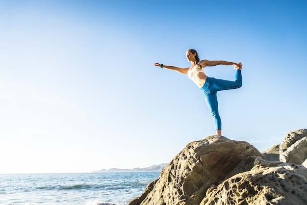 Mujer haciendo yoga en la playa