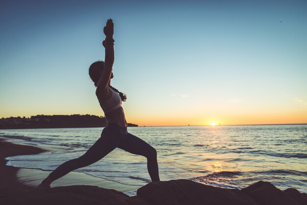 Mujer haciendo yoga en la playa