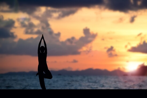 Mujer haciendo yoga en la playa