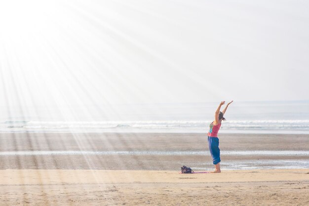 Mujer haciendo yoga en la playa