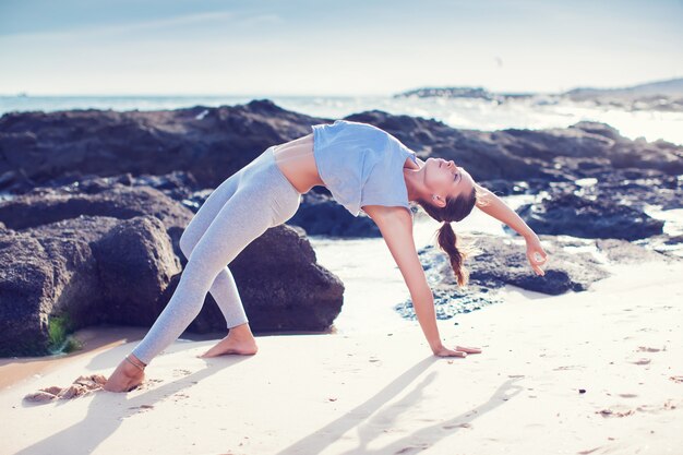 Mujer haciendo yoga en la playa