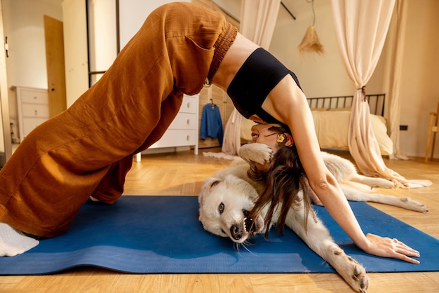 Mujer haciendo yoga con su perro en casa