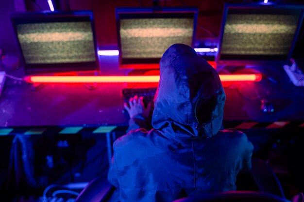 Mujer hacker lleva capucha se sienta frente a la computadora escribiendo en el teclado hacking servidores en luz de neón jugador mujer streaming juego en línea habitación oscura mujer hacker entra en el centro de datos