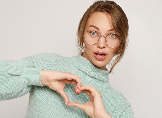 Una mujer hermosa y alegre haciendo el corazón con las manos aisladas en un fondo blanco