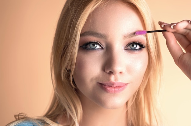 Mujer hermosa aplica gel de cejas con cepillo de cejas a su ceja Retrato de estudio de una mujer joven haciendo maquillaje natural de cejas Concepto de maquillaje de cejas