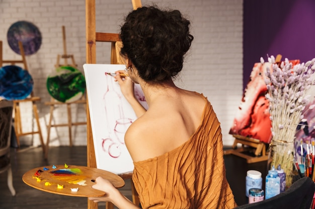 Foto mujer hermosa artística creativa pintando en casa, sosteniendo la paleta