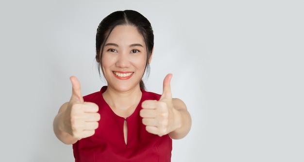 Una mujer hermosa asiática hace un gesto de pulgar hacia arriba con la mano para animar a la gente con una sonrisa y felicidad