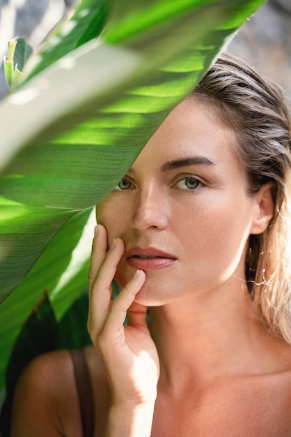 Mujer hermosa y de aspecto natural con hojas de plátano tropical