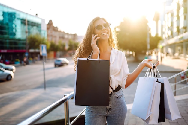 Mujer hermosa con bolsas de compras hace selfie Mujer caminando después de las compras Viernes Negro