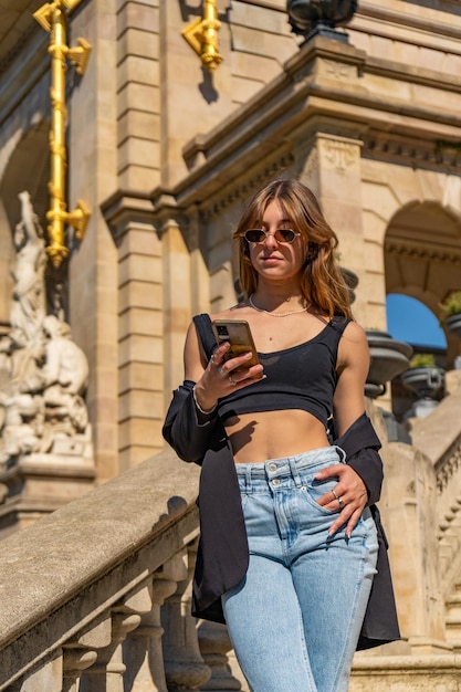 Mujer hermosa bronceada joven en un top negro y jeans con gafas de sol y cabello largo mirando leyendo