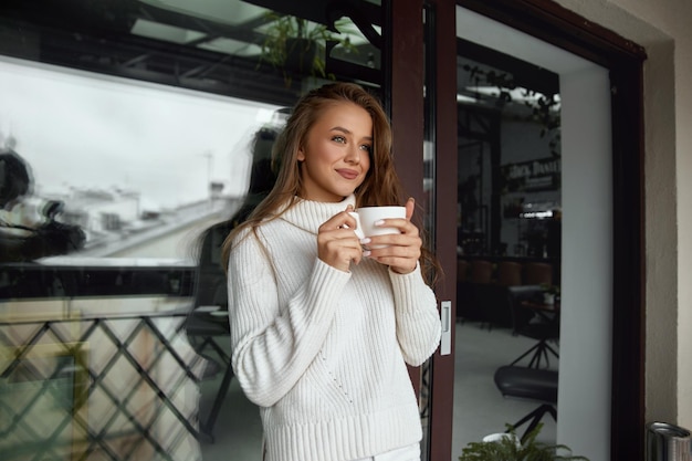 Mujer hermosa en un café bebiendo café y sonriendo