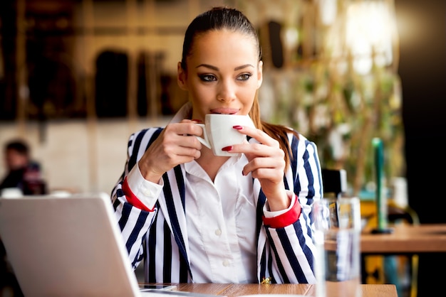 Mujer hermosa en la cafetería tomando café.