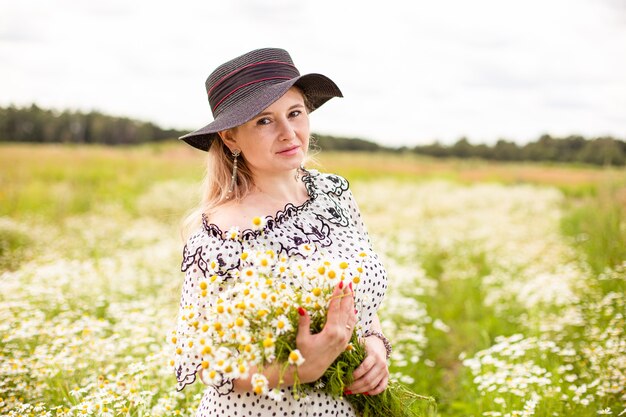 Mujer hermosa en el campo con flores. Foto de alta calidad