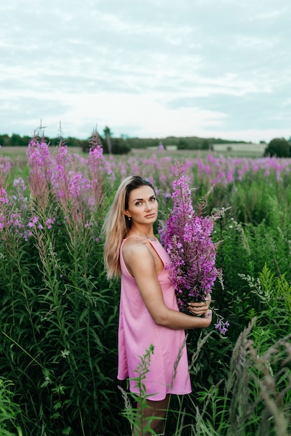 Mujer hermosa en un campo de flores rosadas.