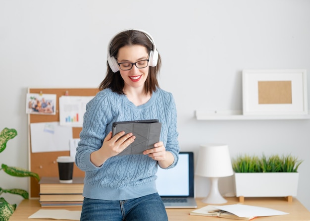 Mujer hermosa casual feliz que trabaja en una tableta en la oficina en casa.