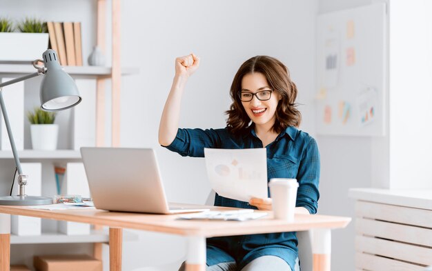 Mujer hermosa casual feliz trabajando en una computadora portátil en casa.