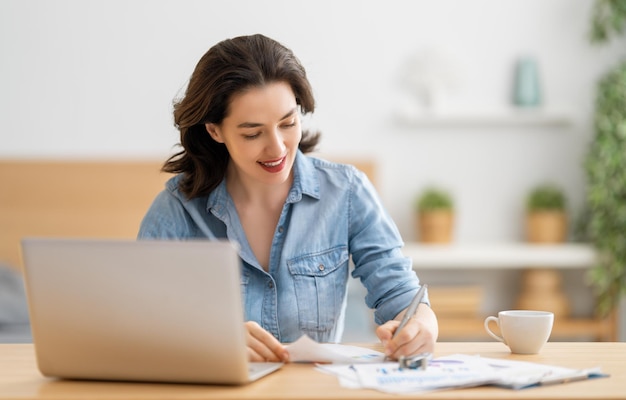 Mujer hermosa casual feliz trabajando en una computadora portátil en casa.