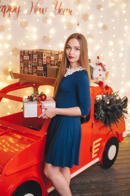 Mujer hermosa en un coche en el interior de Navidad.