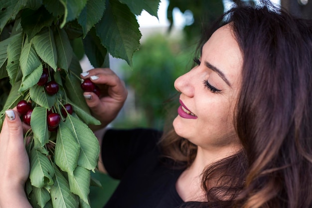 Foto mujer hermosa comiendo cerezas del árbol
