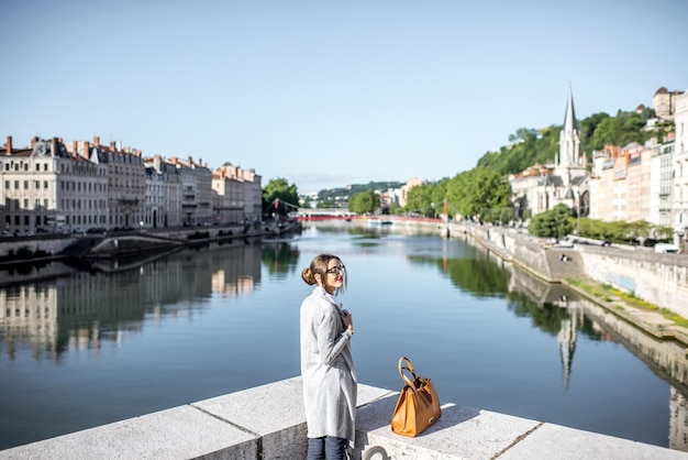 Mujer hermosa y elegante disfrutando de la ciudad de la mañana de pie cerca del río en el casco antiguo de Lyon en Francia