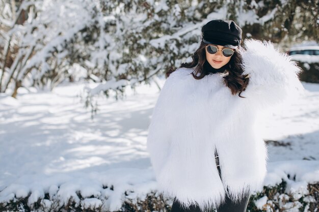 Una mujer hermosa, elegante, de moda en un abrigo de piel, sombrero y gafas