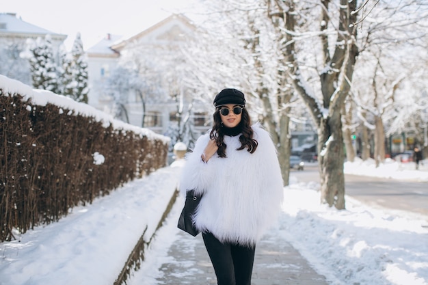 Una mujer hermosa, elegante, de moda en un abrigo de piel, sombrero y gafas