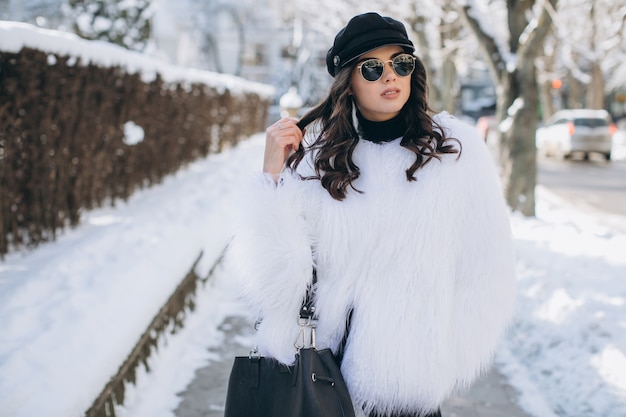 Una mujer hermosa, elegante, de moda en un abrigo de piel, sombrero y gafas