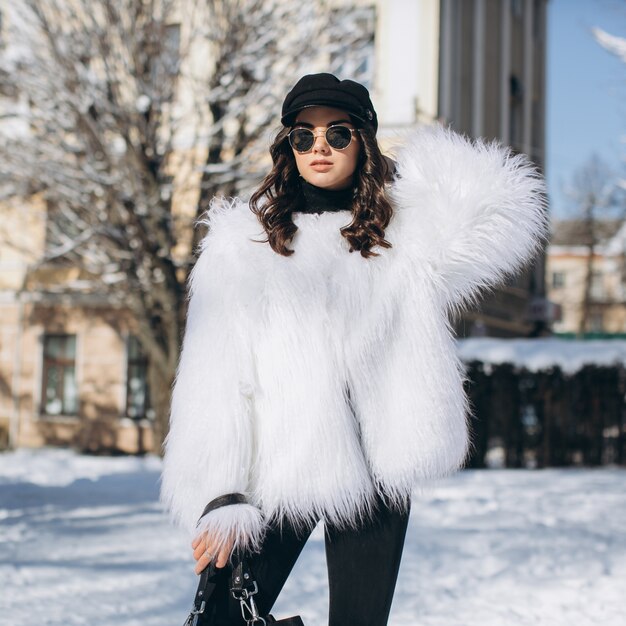 Foto una mujer hermosa, elegante, de moda en un abrigo de piel, sombrero y gafas