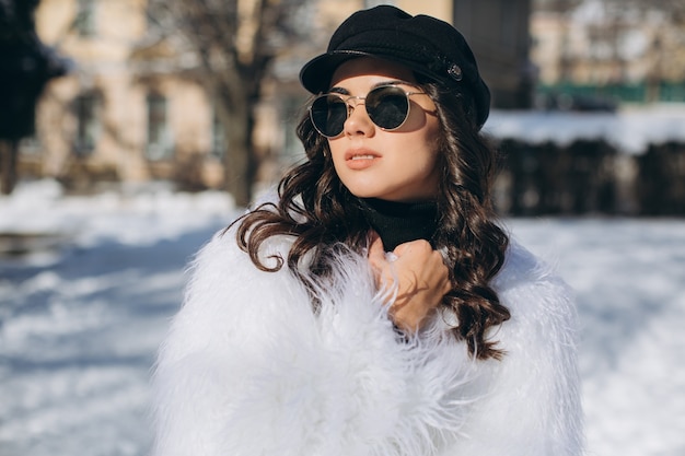 Una mujer hermosa, elegante, de moda en un abrigo de piel, sombrero y gafas