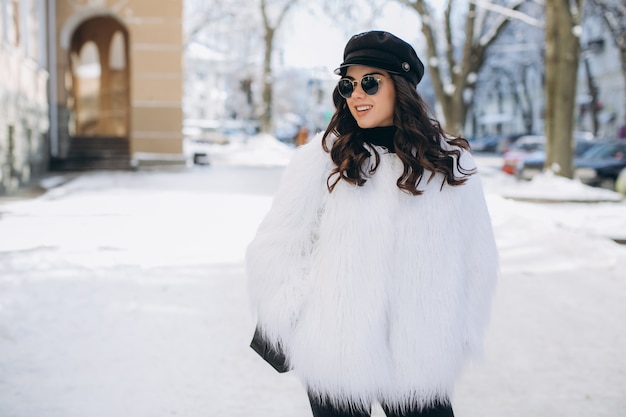 Una mujer hermosa, elegante, de moda en un abrigo de piel, sombrero y gafas