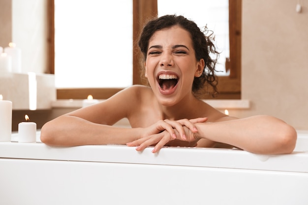 Mujer hermosa emocionada emocional en el baño se encuentra descansando en el baño.