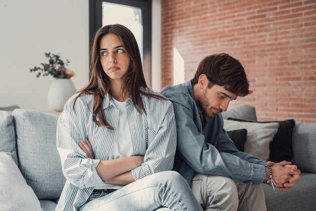 Una mujer hermosa está deprimida sentada en el sofá hablando con un hombre teniendo una disputa con su marido o novio pareciendo desesperada y sin esperanza teniendo un problema o pregunta sin resolver
