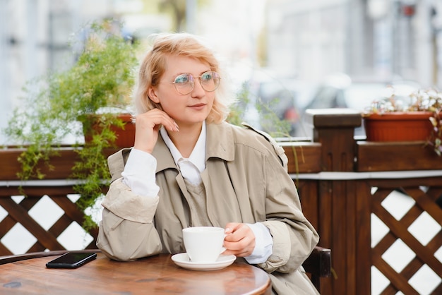 Mujer hermosa con estilo joven sentada en el café de la ciudad en la calle