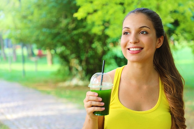 Mujer hermosa feliz con batido verde