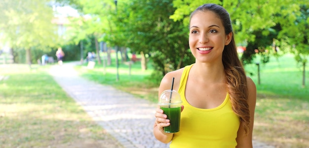 Mujer hermosa feliz con batido verde