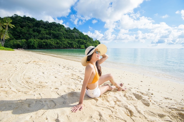 Una mujer hermosa feliz en bikini amarillo disfrutando y relajándose en la playa, el concepto de verano y vacaciones